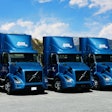 A row of Volvo VNR Electric Trucks parked outside.