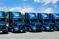 A row of Volvo VNR Electric Trucks parked outside.