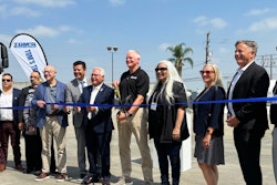 A group of people cutting a blue ribbon in front of a Nikola truck.