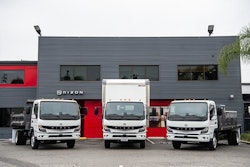 Three trucks in front of a gray metal building
