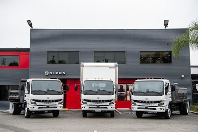 Three trucks in front of a gray metal building