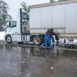 Truck driver adding chains in snow weather