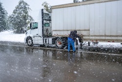 Truck driver adding chains in snow weather