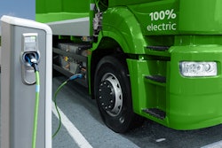 A rendering of an electric semi truck plugged in at a charging station.