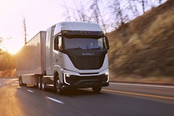 A Nikola Tre semi driving on a highway at sunset.