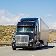 A diesel-powered Class 8 semi truck driving on a Southern California highway.