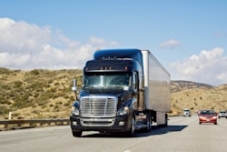 A diesel-powered Class 8 semi truck driving on a Southern California highway.