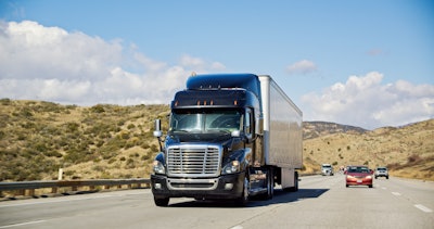 A diesel-powered Class 8 semi truck driving on a Southern California highway.