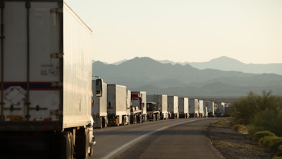 Semi trucks lined up on a crowded California highway.