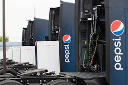 Pepsi-branded Tesla Semis parked at a charging stalls.