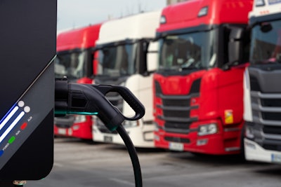 Battery-electric semi trucks parked next to each other waiting to recharge.