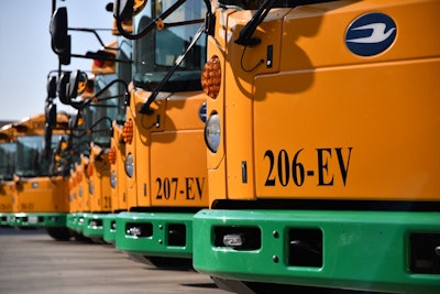 Blue Bird RE Electric school buses lined up in a parking lot.