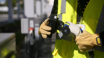 A ChargeHelp! technician is shown testing an EV charging connector.