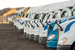 A fleet of commercial semi trucks lined up waiting for refueling and hauling duties.
