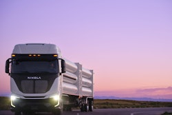 A Nikola Tre Class 8 semi driving on a highway hauling a HYLA-branded hydrogen for refueling payload.