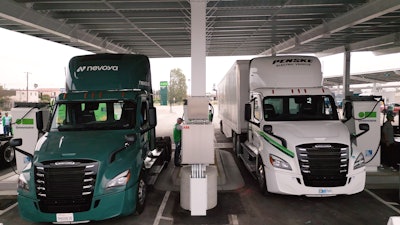 Two Class 8 battery-electric semis are shown parked at a Greenlane charging depot.