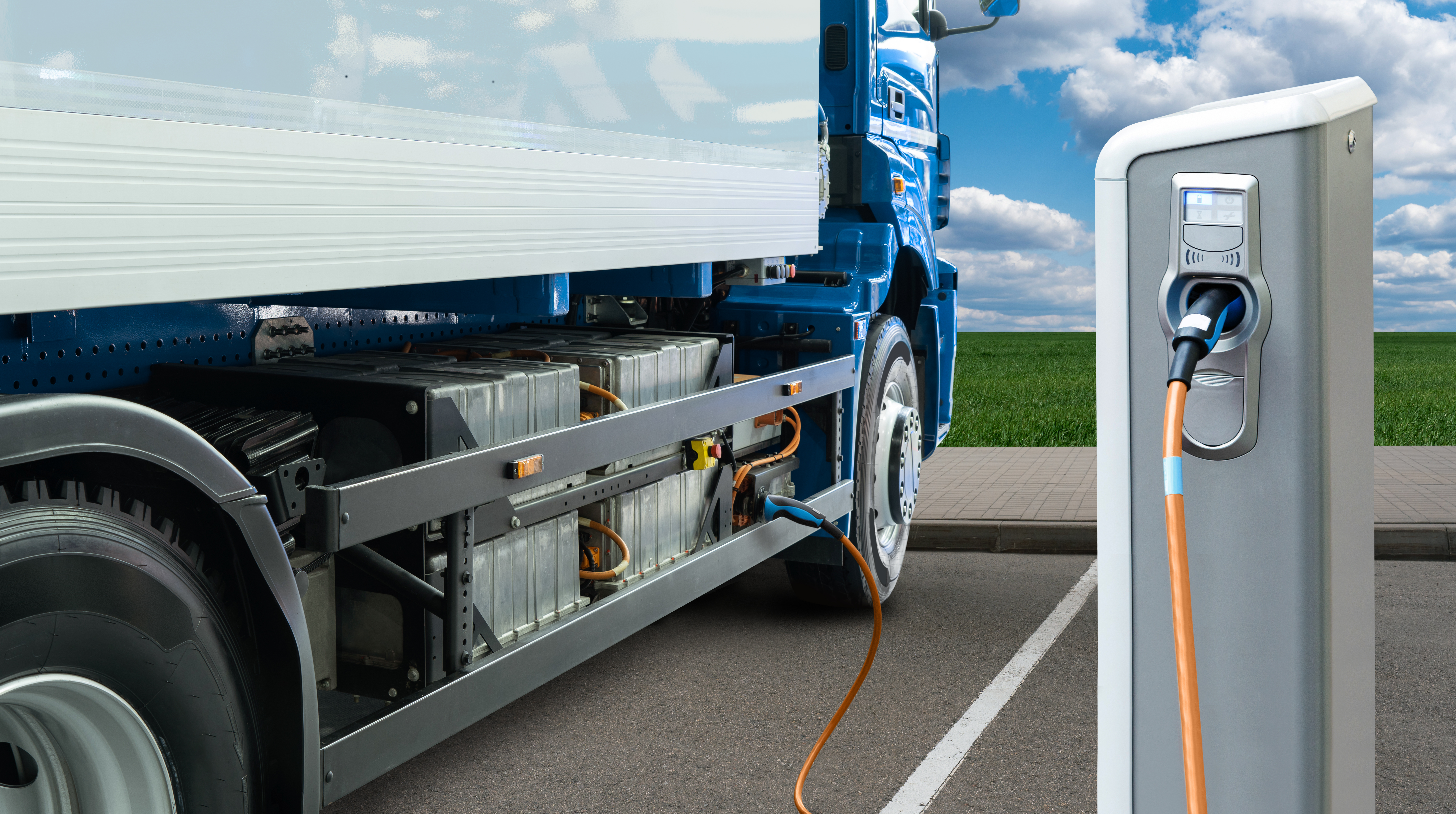 A battery-electric semi truck charging at a station, illustrating EV infrastructure in action.