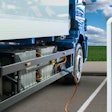 A battery-electric semi truck charging at a station, illustrating EV infrastructure in action.