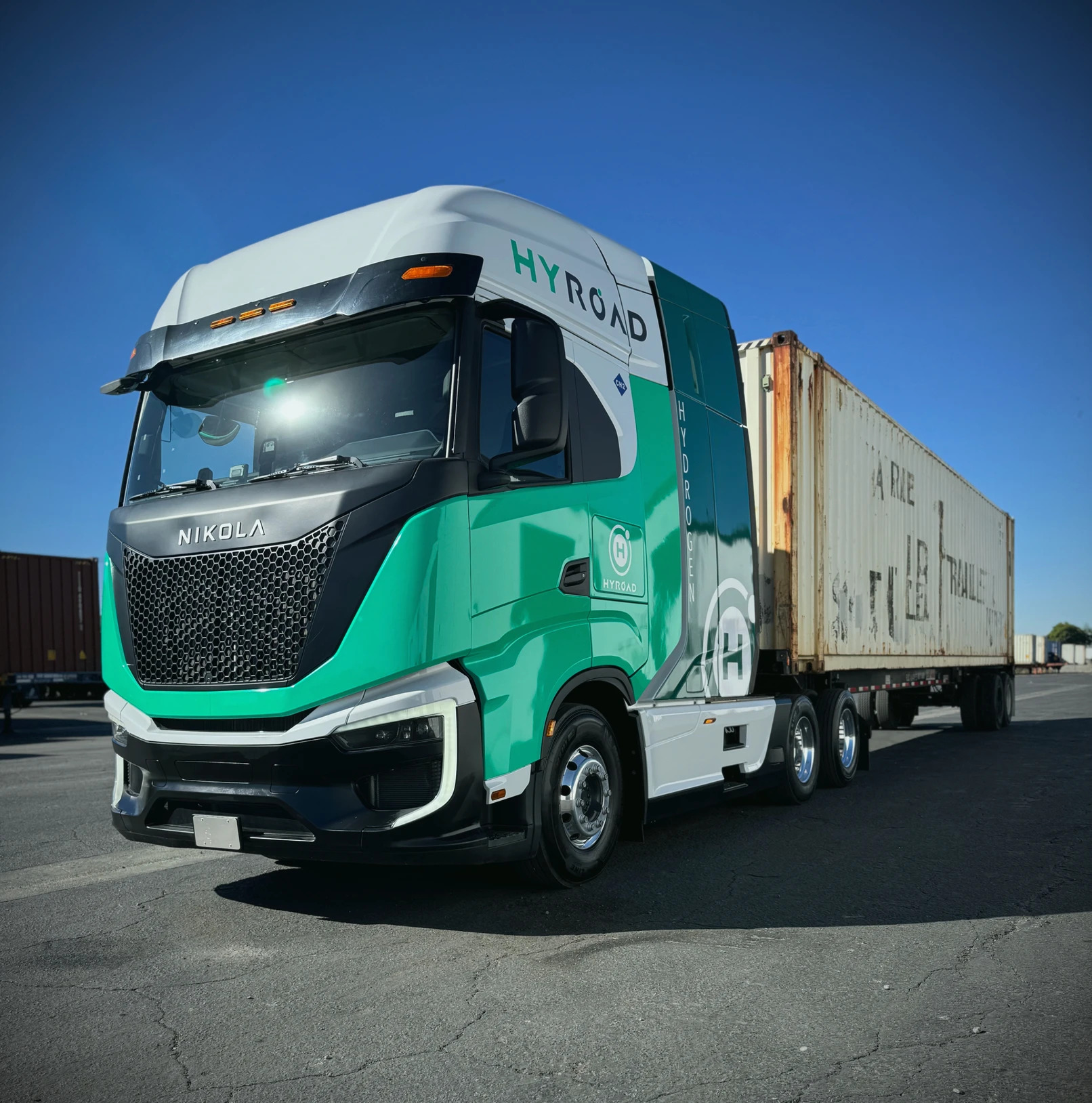 A Hyroad Energy-liveried Nikola Tre FCEV semi parked outside with a trailer attached.