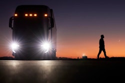 A person walks away from a parked Nikola FCEV semi at sunset.