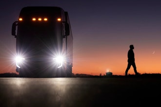 A person walks away from a parked Nikola FCEV semi at sunset.