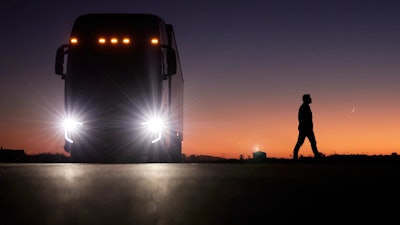 A person walks away from a parked Nikola FCEV semi at sunset.