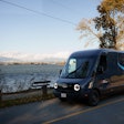 A Rivian Electric Delivery Van operates against the Vancouver skyline as Amazon launches its first EV fleet in Canada.