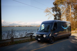 A Rivian Electric Delivery Van operates against the Vancouver skyline as Amazon launches its first EV fleet in Canada.
