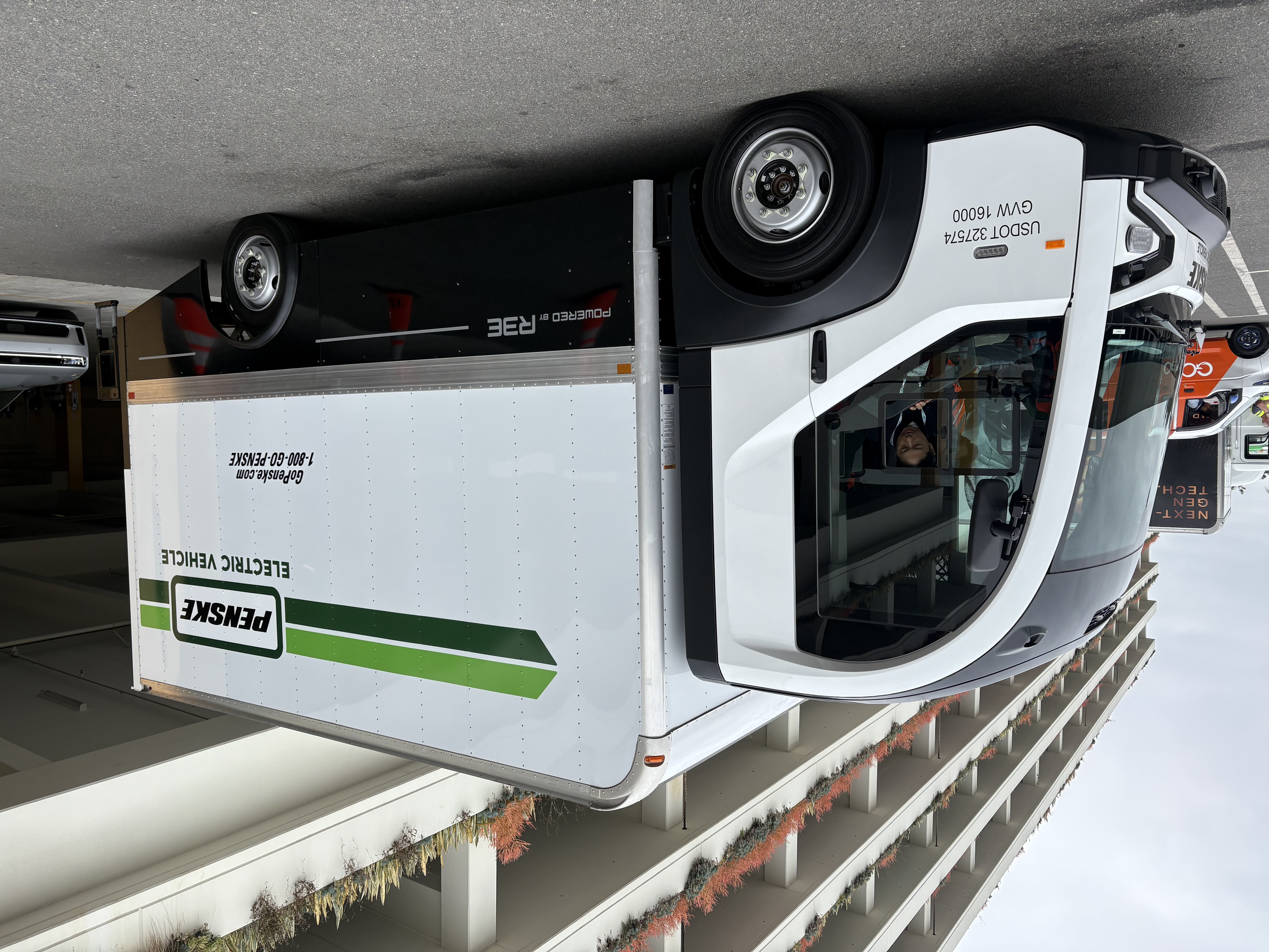 The battery-electric REE Automotive P7 Chassis Cab parked next to a building at the ACT Expo 2025.