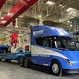 RoadOne's newly acquired blue Tesla Semi unloads aluminum coils inside a warehouse.