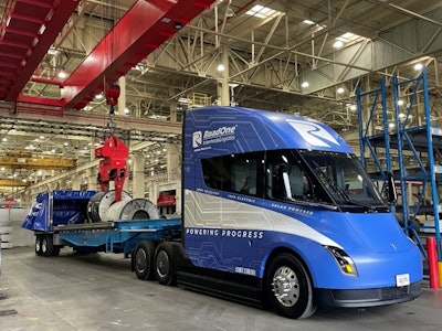 RoadOne's newly acquired blue Tesla Semi unloads aluminum coils inside a warehouse.