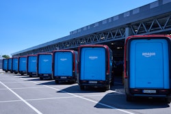 Amazon-branded Rivian Electric Delivery Vans lined up at a logistics center.