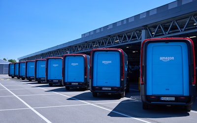Amazon-branded Rivian Electric Delivery Vans lined up at a logistics center.