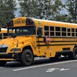 A yellow battery-electric school bus built by Blue Bird is parked.