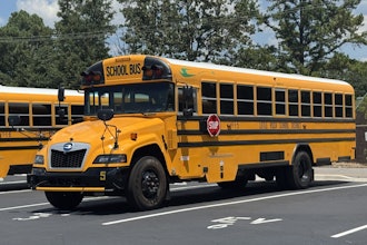A yellow battery-electric school bus built by Blue Bird is parked.