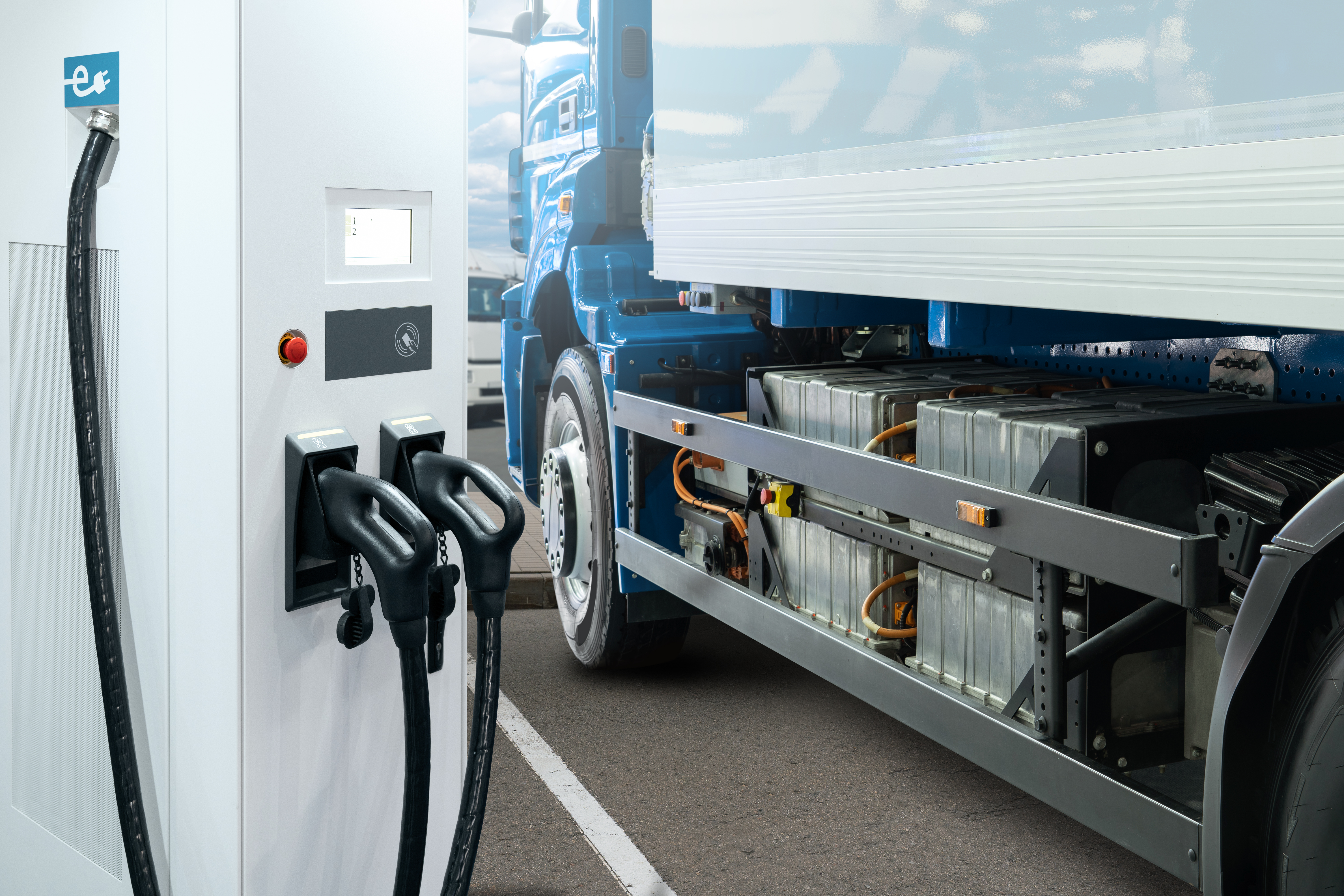 A rendering of a battery-electric semi truck parked next to a charging station.