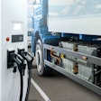A rendering of a battery-electric semi truck parked next to a charging station.