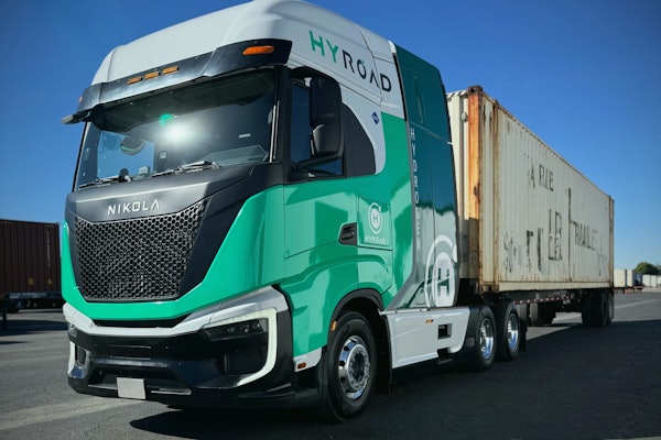 A hydrogen-powered Nikola Tre semi wrapped in a Hyroad Energy livery with a cargo trailer.
