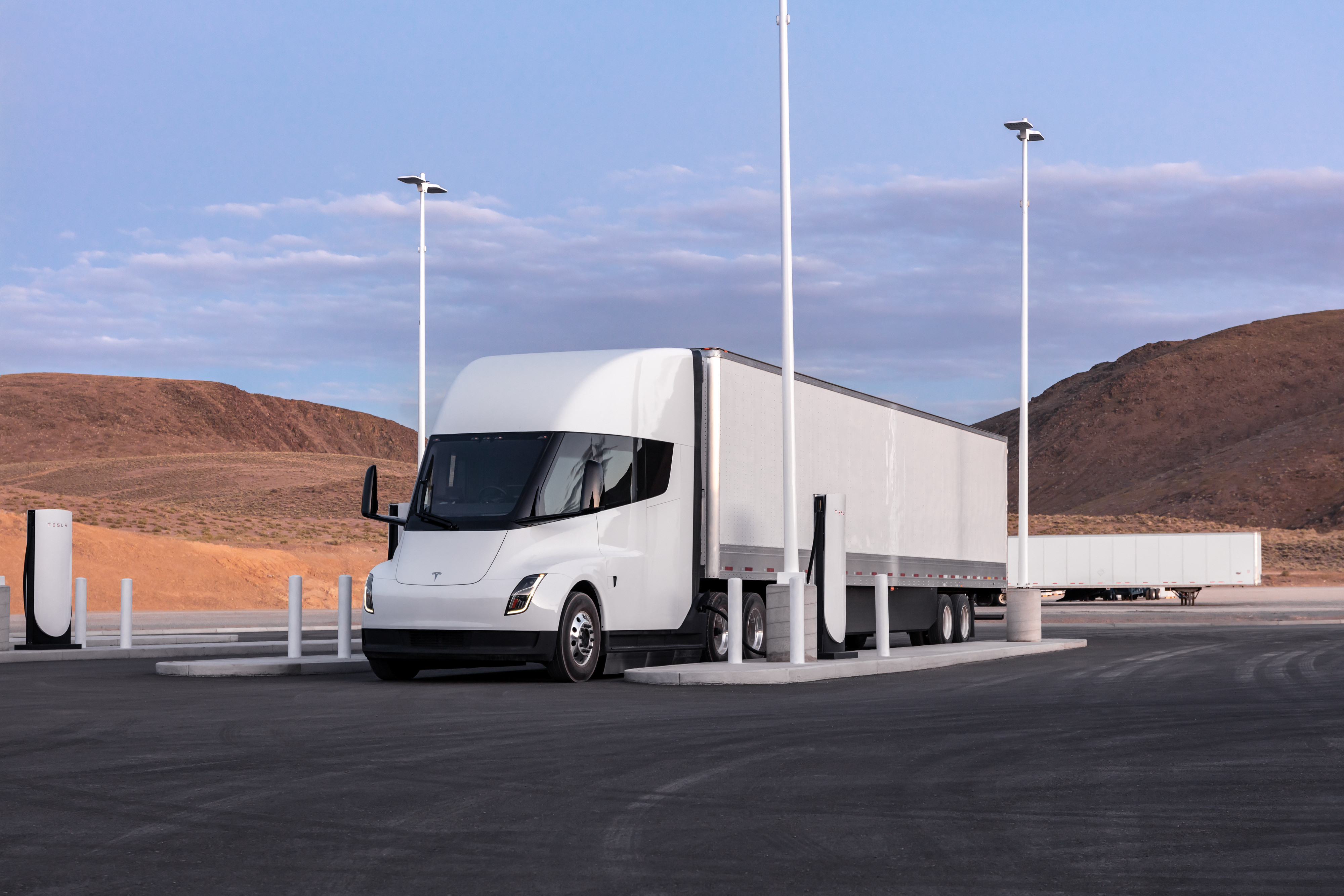 A rendering of a white Tesla Semi at a charging station.