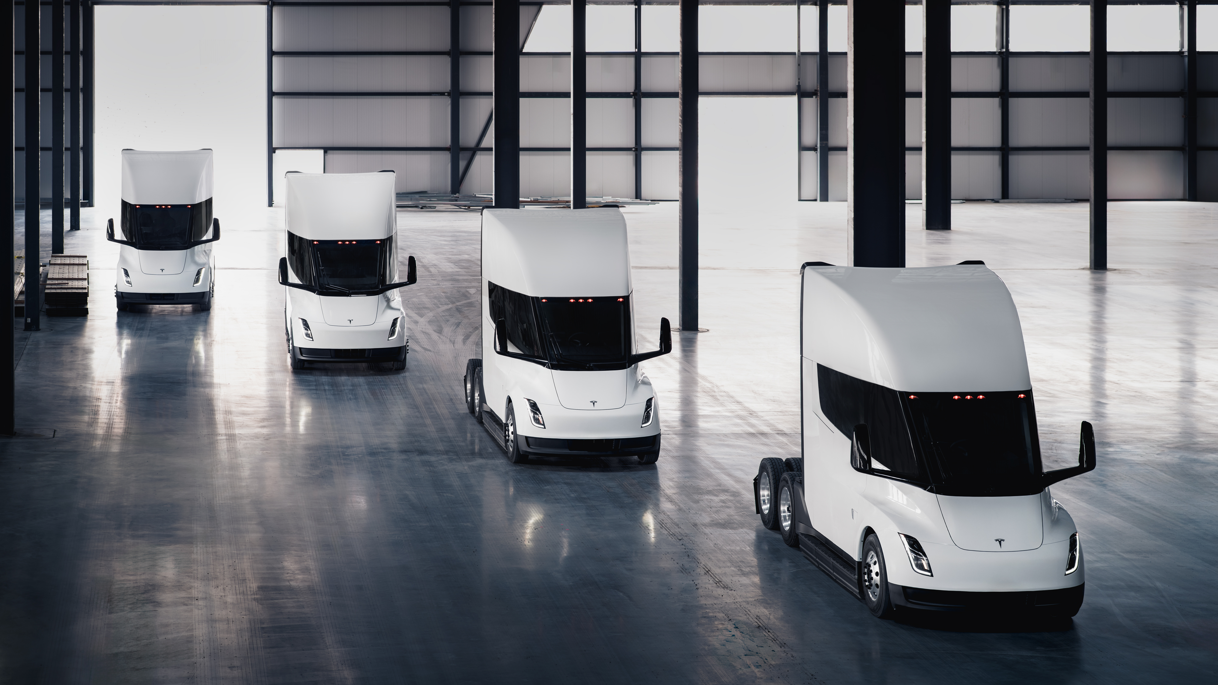 A rendering of four Tesla Semi battery-electric Class 8 trucks parked inside a warehouse.