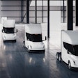 A rendering of four Tesla Semi battery-electric Class 8 trucks parked inside a warehouse.