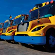 A row of bright yellow Lion Electric school buses lined up in an outdoor parking lot.