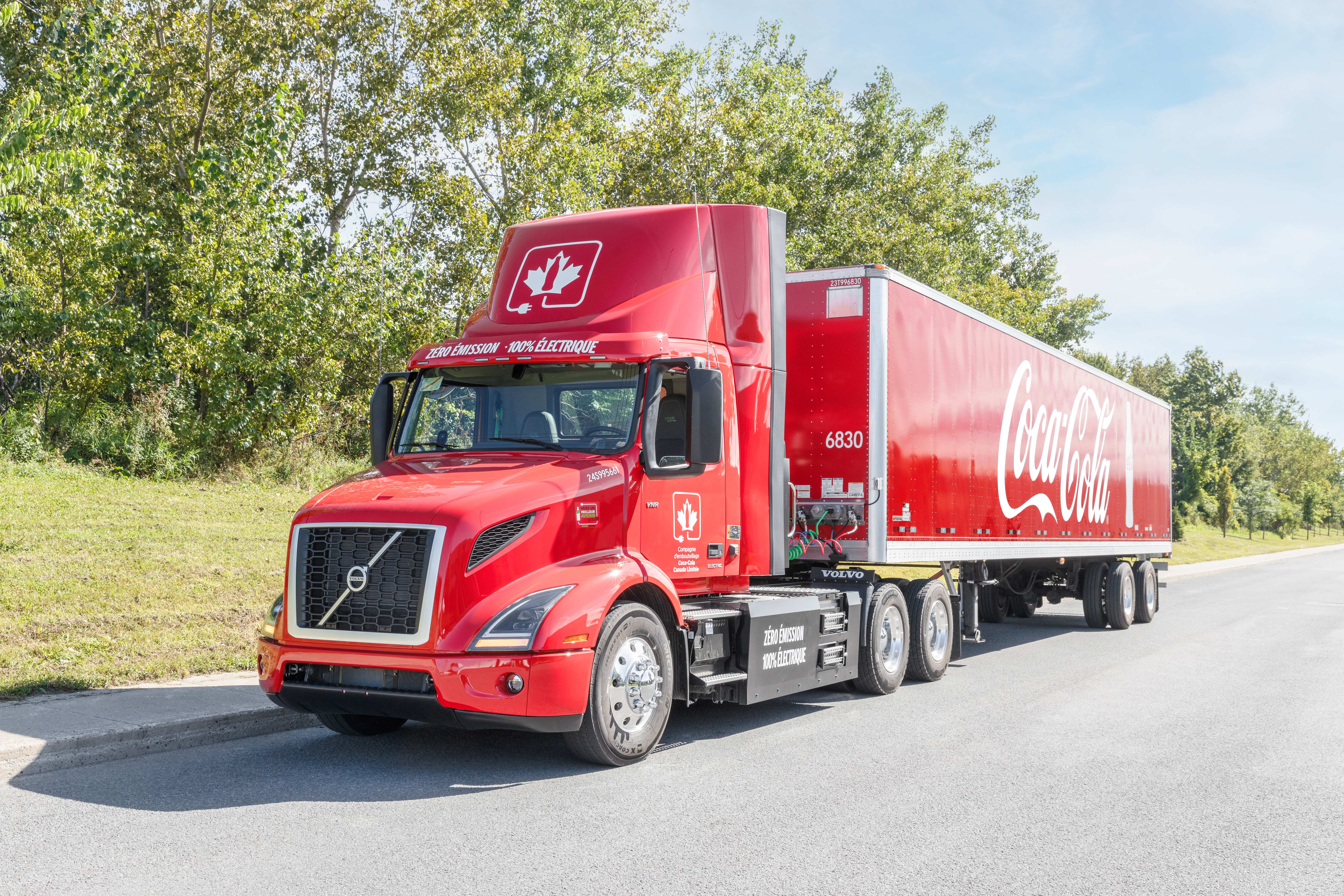 Coke Canada Bottling's read Volvo VNR Electric hauling a red Coca-Cola trailer.