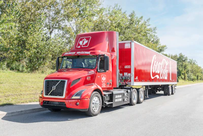 Coke Canada Bottling's read Volvo VNR Electric hauling a red Coca-Cola trailer.