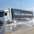 Mercedes-Benz's NextGenH2 hydrogen fuel cell truck undergoes a wet pavement handling test, with water sprayed across the surface to simulate real-world conditions.