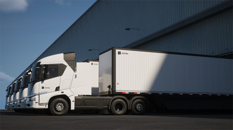 Einride battery-electric semi-trucks parked in front of an industrial warehouse.