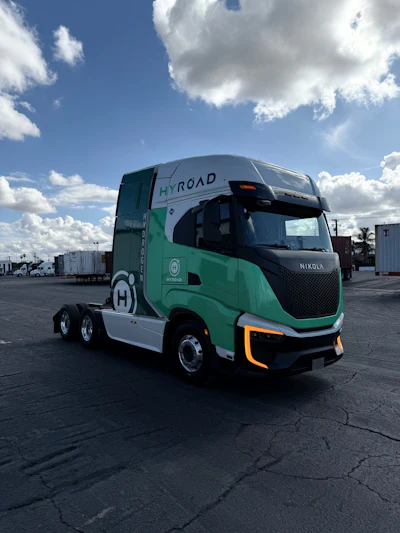 A Nikola Tre FCEV semi truck with green and white Hyroad Energy livery.