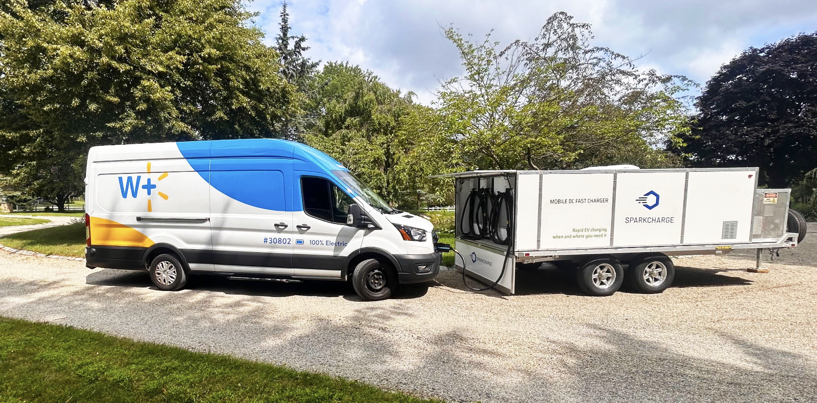 A battery-electric Walmart delivery van connected to a SparkCharge mobile charging unit for on-demand fleet charging.