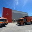 Two orange Mack LR refuse trucks parked outside of a Kingston, Ontario, Canada industrial building.