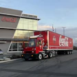 A Coca-Cola-branded Orange EV terminal truck hauling a Coca-Cola trailer outside Coke Canada Bottling's headquarters.